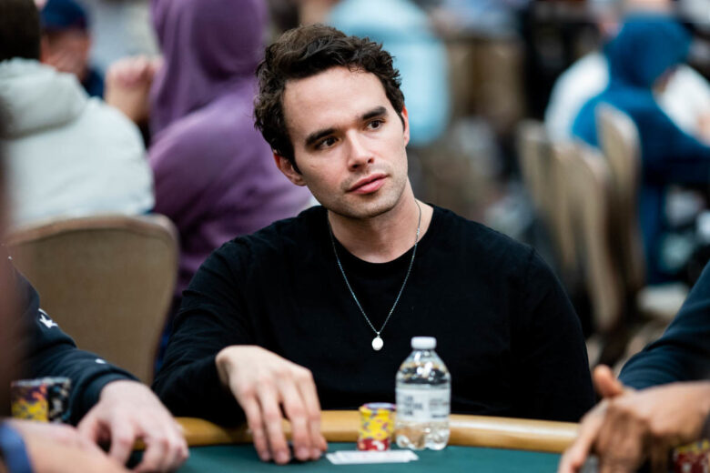 Alex Keating in Los Angeles, standing in front of a poker-themed mural, holding a pair of poker chips.