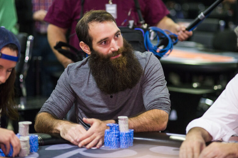 A lively poker tournament with Alex Keating at the forefront, surrounded by players and spectators. 