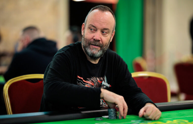 A candid shot of Andy Black, deep in thought at a poker table, as the crowd watches in anticipation.